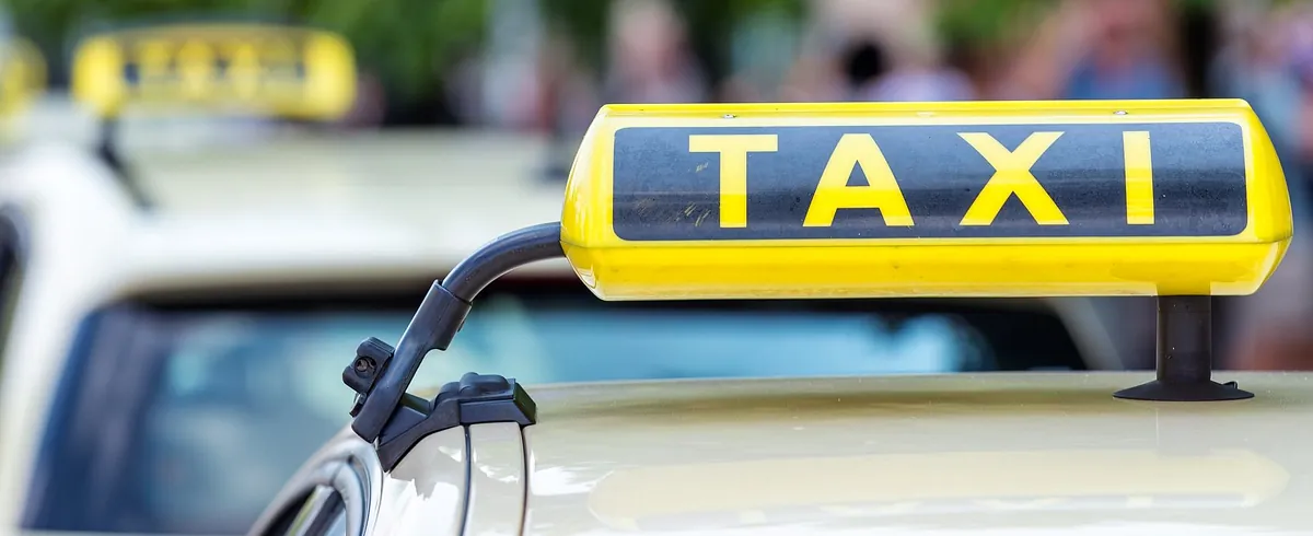 Nahaufnahme von einem Taxischild, im Hintergrund weitere Taxis