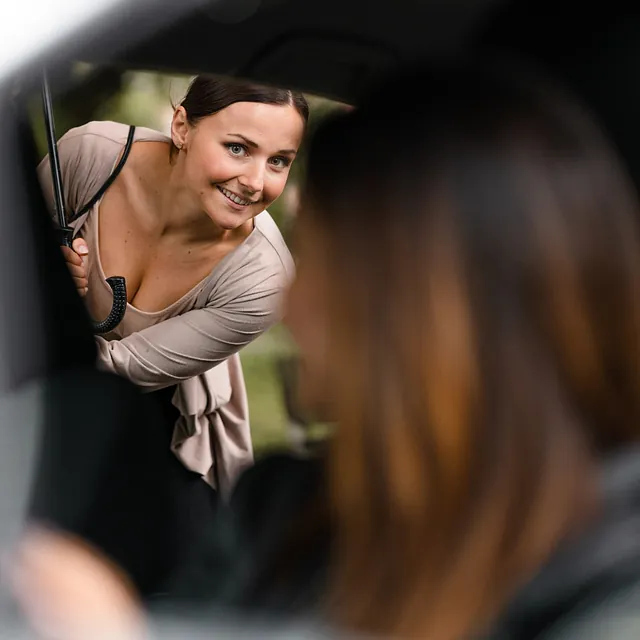 Frau verabschiedet sich von Freundin im Taxi 